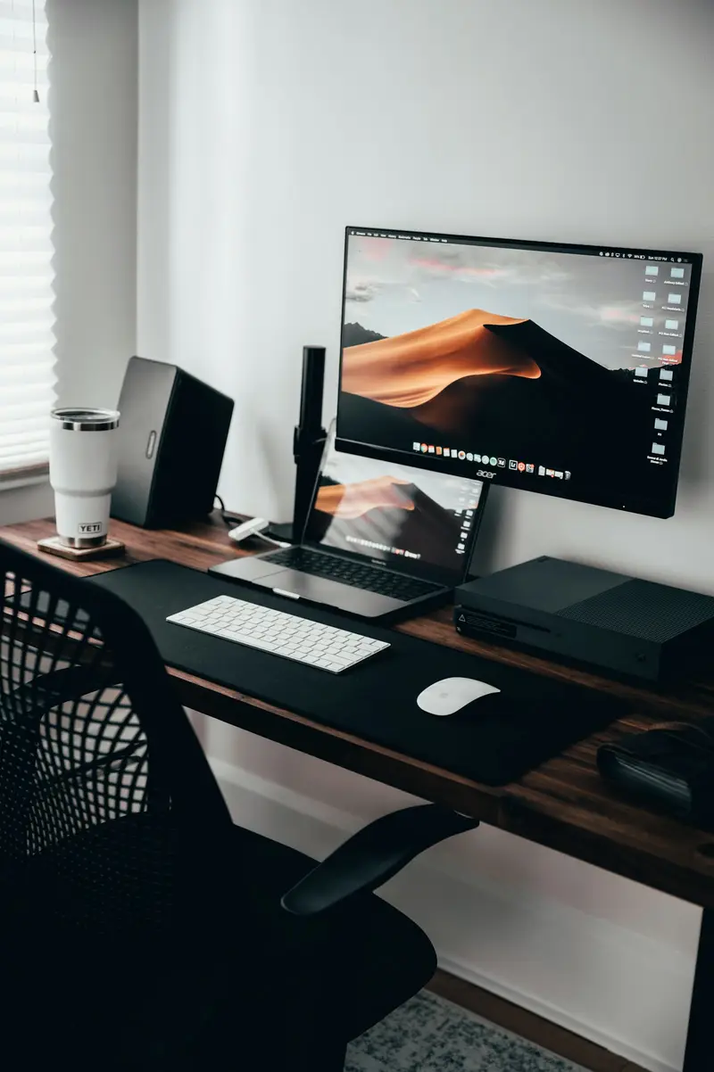 A tidy home office desk with a monitor, keyboard and chair
